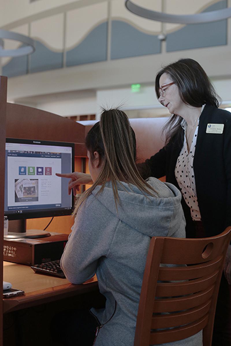A photo of a CSN librarian assisting a student at a computer
