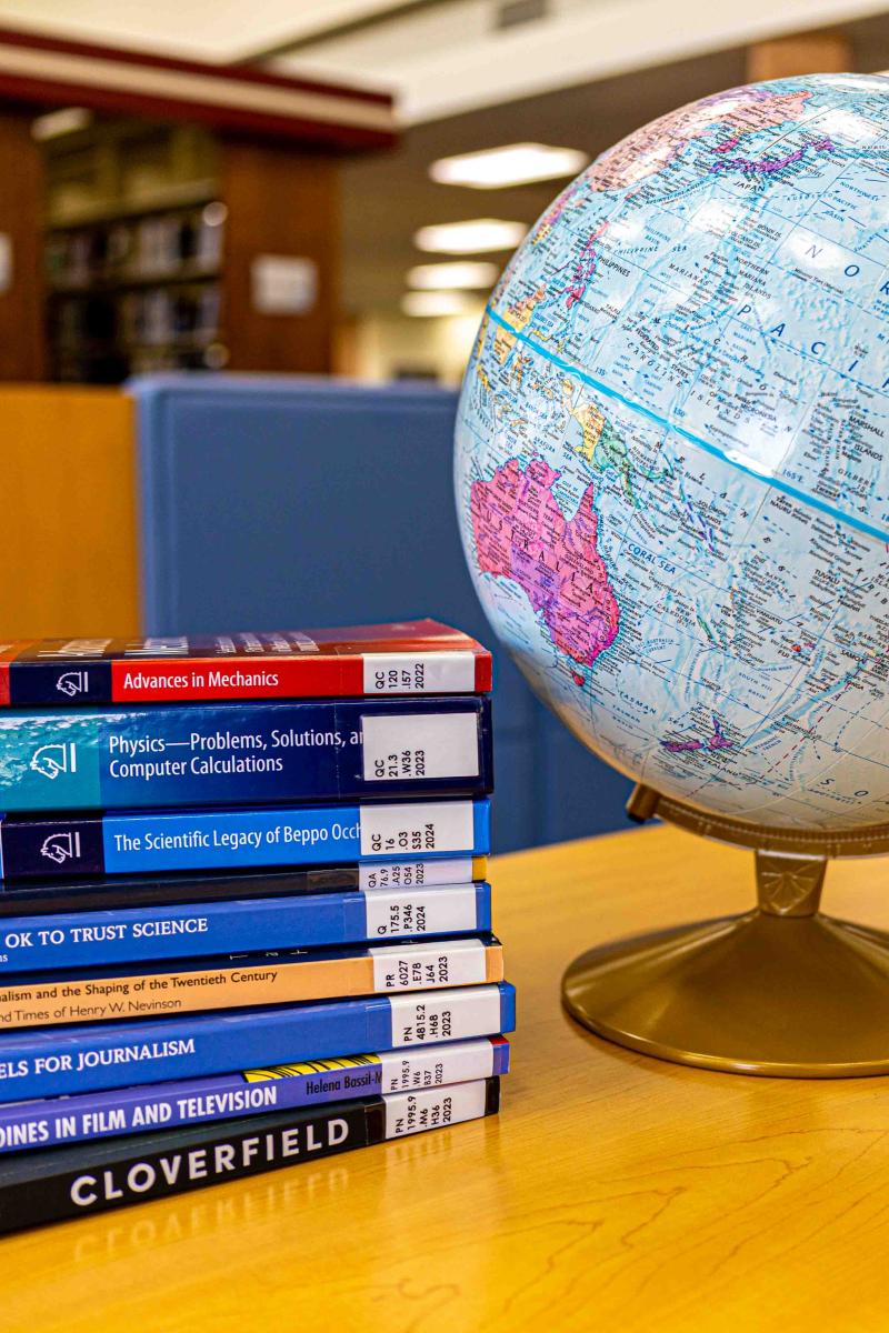 A photo of a stack of books next to a globe